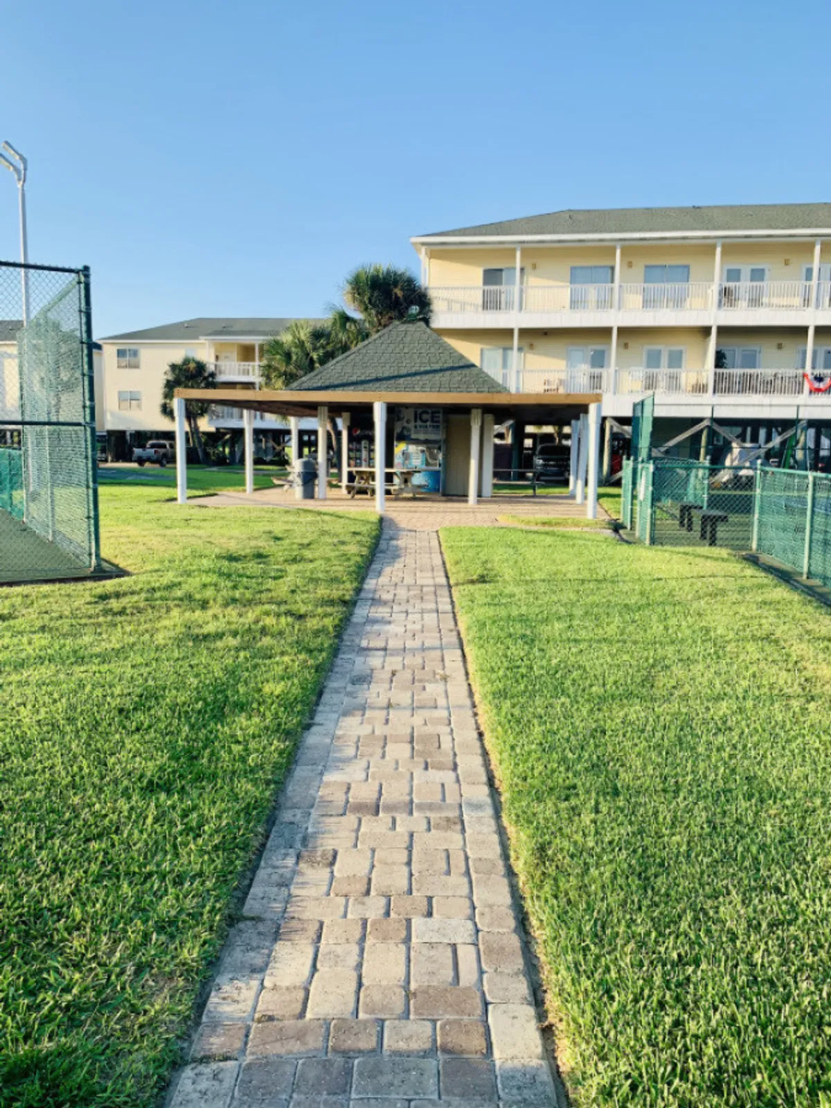 A landscaped pathway leads to a pavilion surrounded by greenery. The area is spacious, with open lawns and shaded gathering spots ideal for strolls, outdoor activities, or quiet moments with pets.